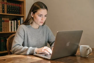 Femme utilisant l'extension LanguageTool sur un ordinateur portable dans un bureau à domicile, expression sceptique et réfléchie