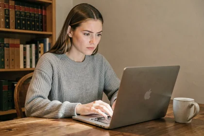 Femme utilisant l'extension LanguageTool sur un ordinateur portable dans un bureau à domicile, expression sceptique et réfléchie