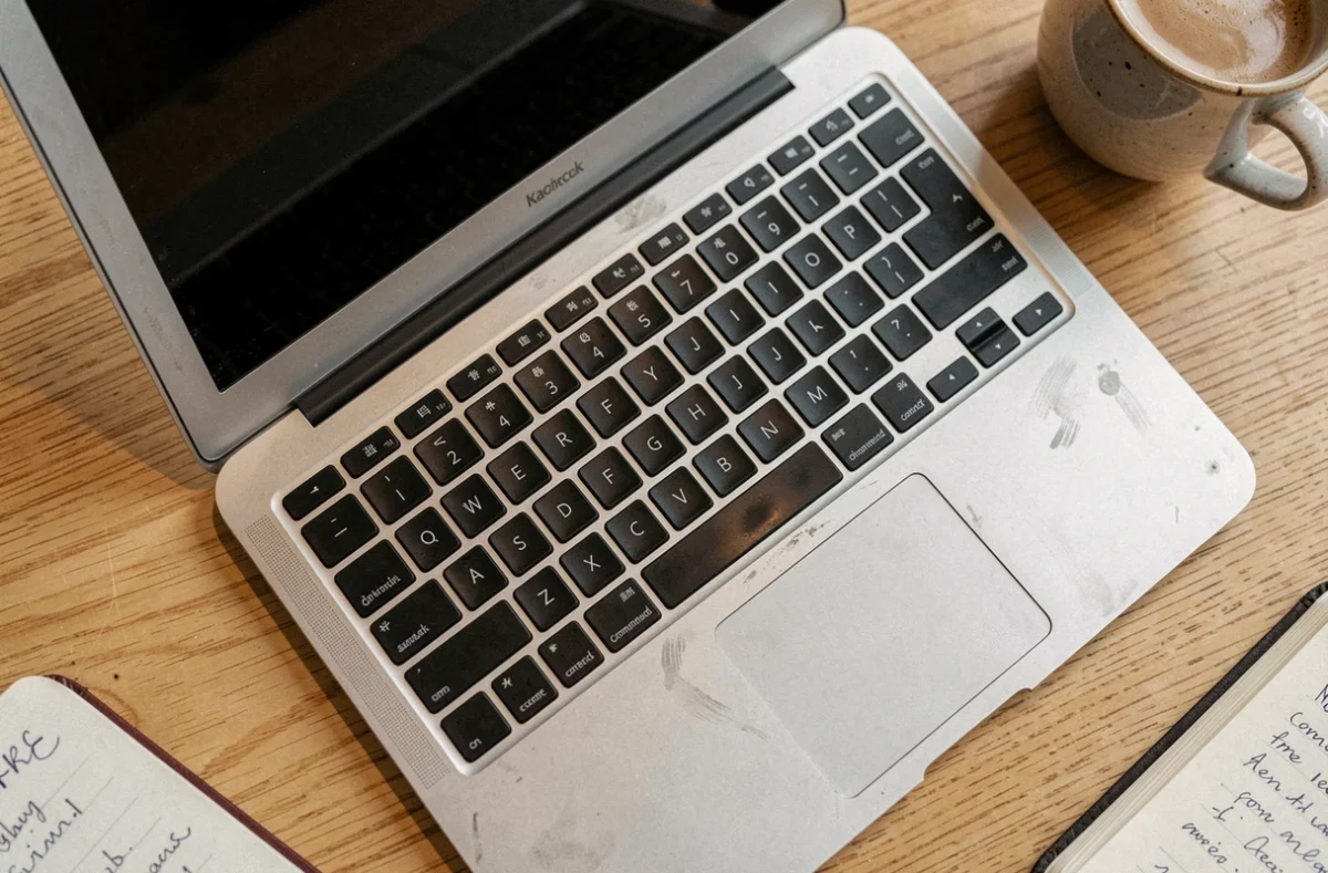 Gros plan sur un MacBook Air ancien révélant les signes d'usure après plusieurs années d'utilisation intensive